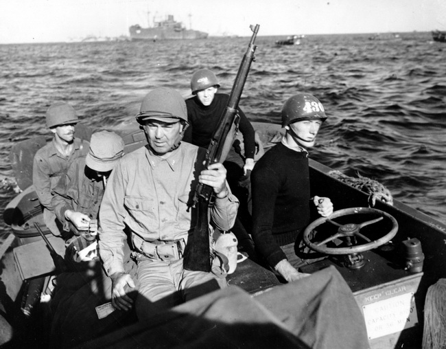 Commander Jack Dempsey, holding rifle, rides a Coast Guard landing craft to the Okinawa Beach in the Philippines a few hours after the initial attack began on the Japanese Ryuku Island in April, 1945 during World War II.  apruarena1_WWII_U.S._001P0.jpg