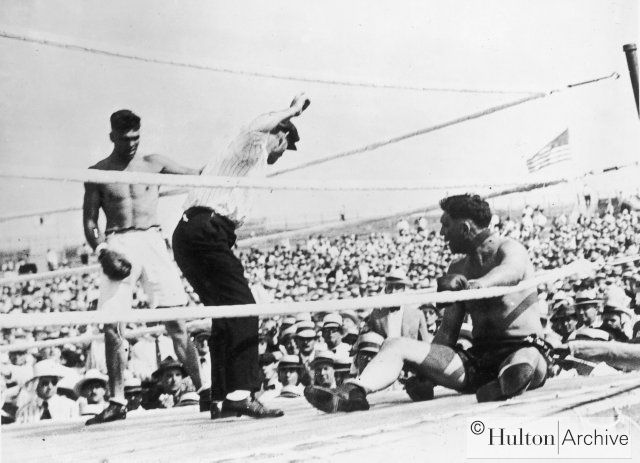 Jess Willard sits up after being knocked to the floor by Jack Dempsey during their world heavyweight title fight at Toledo, Ohio. Dempsey won the fight at the end of the third round after Willard's second threw in the towel, and he held onto the title 2 Дэмпси-Уиллард.jpg